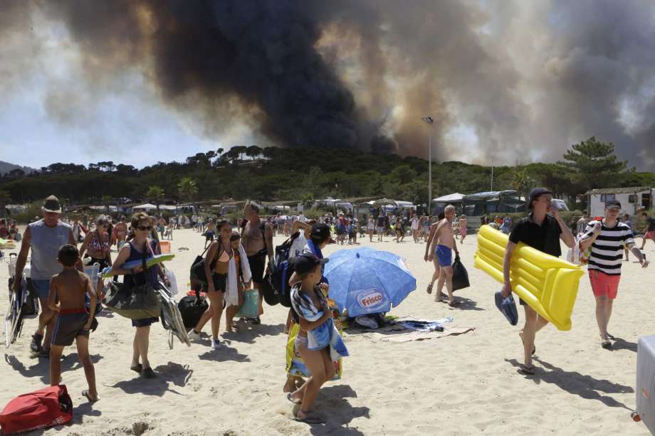 Sunbathers are being evacuated from the beach in Le Lavandou French Riviera as plumes of smoke rise in the air from burning wildfires Wednesday