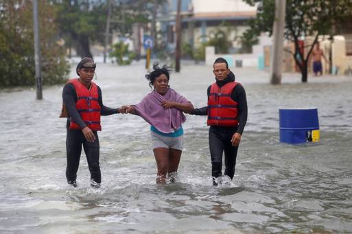 Rescue personnel help a woman through floods after the passing of Hurricane Irma in Havana Cuba