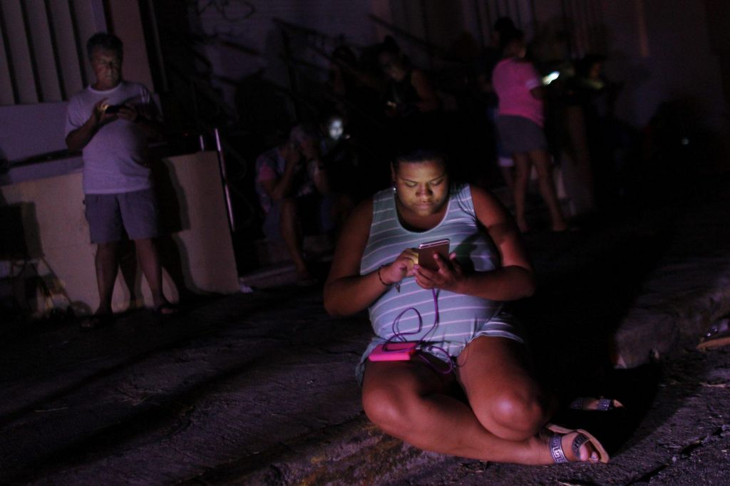 A woman checks her cellphone next to a road at night in one of the few places with cell signal access in San Juan Puerto Rico on Sept. 25 2017