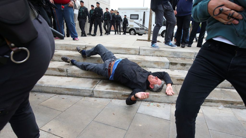 A man falls to the ground during scuffles with Spanish police