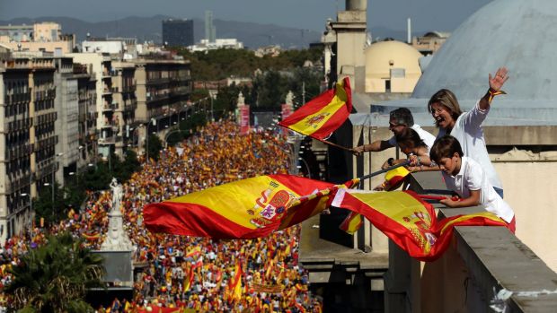 People on a rooftop wave Spanish flags during a march in downtown Barcelona Spain to protest the Catalan government's