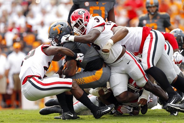 Tennessee running back John Kelly is tackled by Georgia defensive back J.R. Reed and linebacker Roquan Smith during the first half of an NCAA college football game Saturday Sept. 30 2017 in Knoxville Tenn