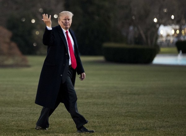 President Donald Trump gestures as he responds to reporters asking questions as he walks on the South Lawn upon his return to the White House in Washington Thursday Dec. 21 2017