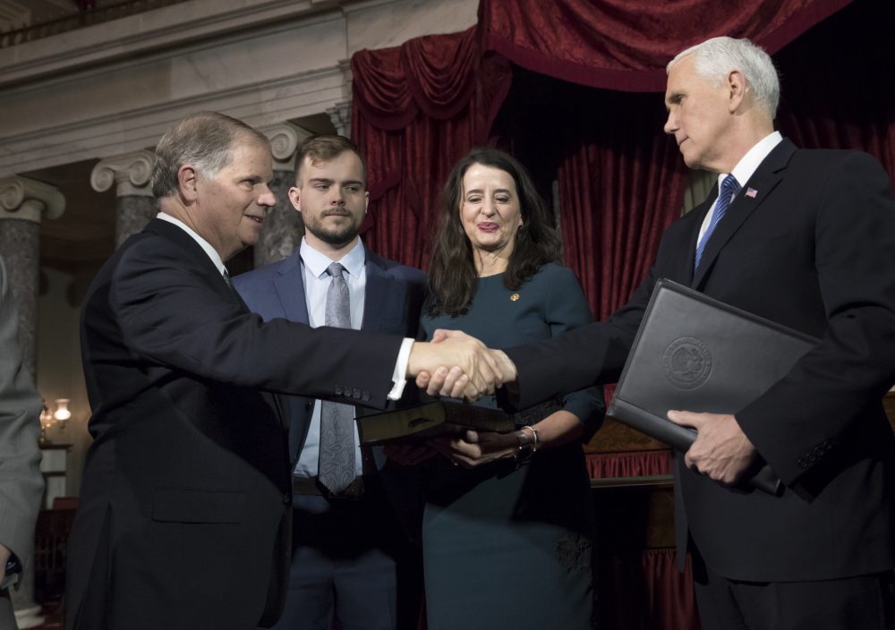 Vice President Mike Pence right shakes hands with Sen. Doug Jones D-Ala. left after administering the Senate oath of office during a mock swearing in ceremony in the Old Senate Chamber to Jones with his wife Louise Jones second from right Wednesda