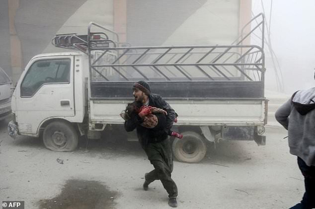 A man carries a child as he flees from reported Syrian air strikes in rebel-held Eastern Ghouta