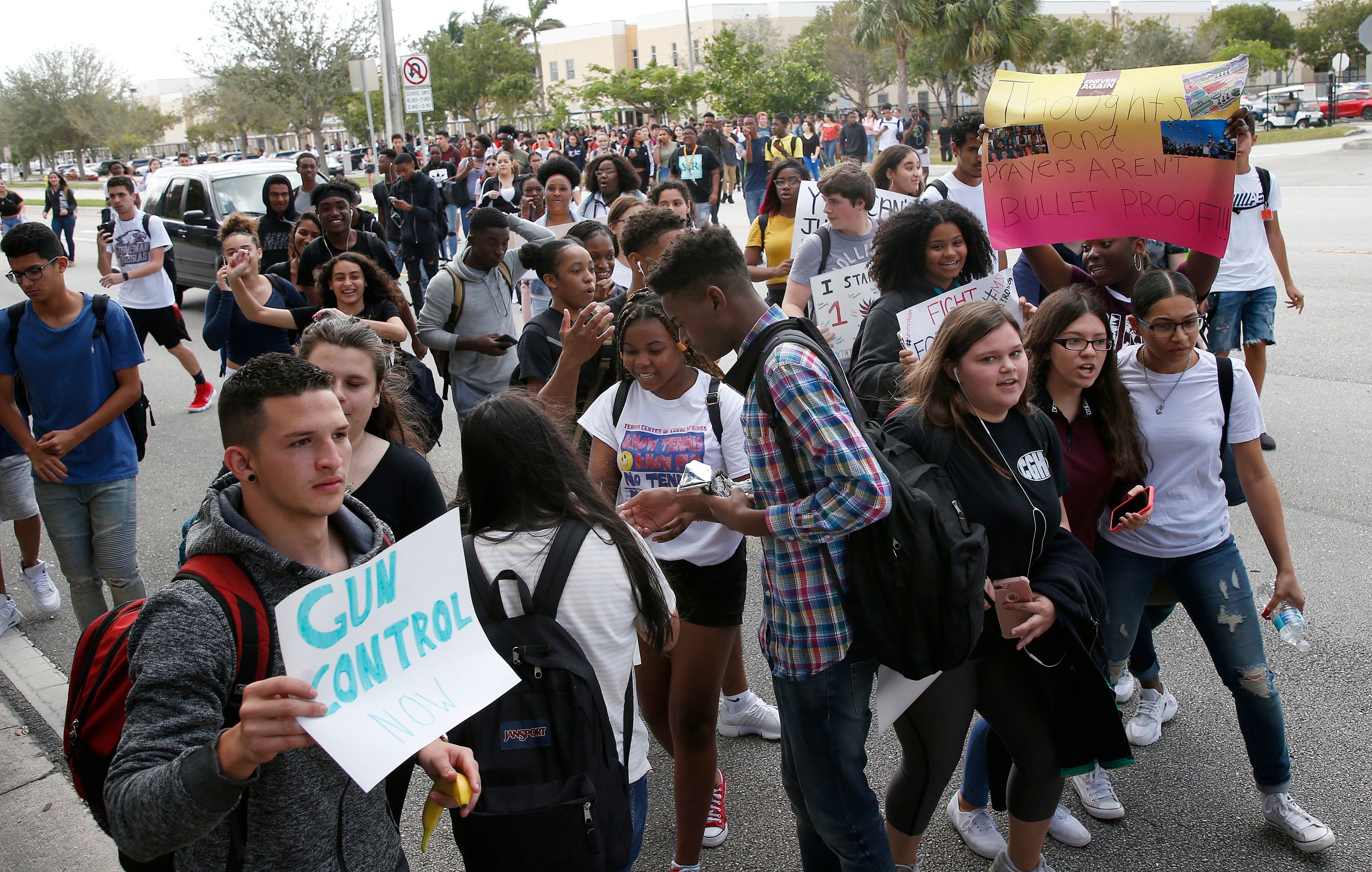 Students of Coral Glades High School a high school less than four miles from Douglas hold signs as the participate in a school walk for gun law change at Coral Glades High School in Coral Springs Florida