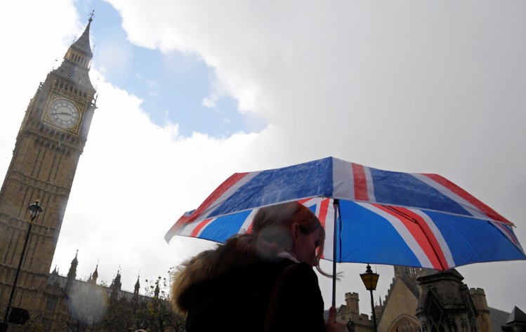 British union flag design umbrella as she walks past the Houses of Parliament in London Britain