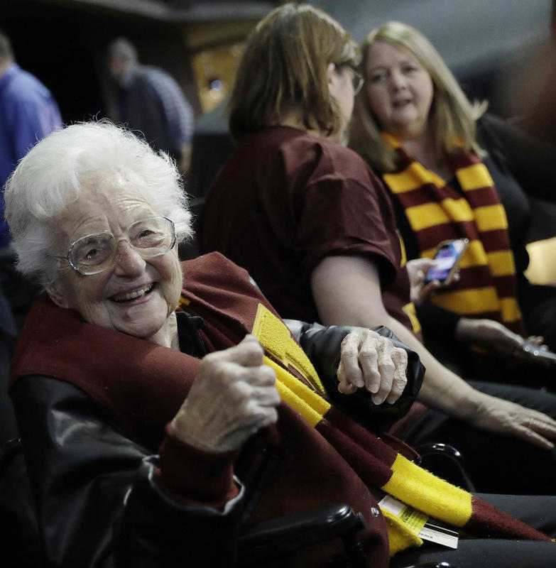 Dolores Schmidt sitting with other Loyola Chicago fans during the first half of a regional semifinal NCAA college basketball game against Nevada in Atlanta. Sister Jean is depicted in a bobblehead