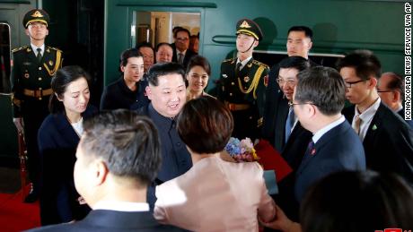 Kim Jong Un center and his wife Ri Sol Ju center right are greeted by Chinese officials in Beijing