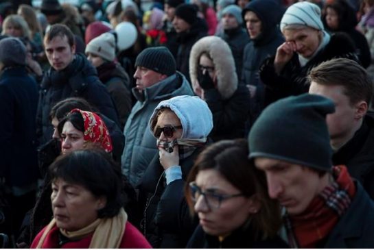 People react as they bring flowers toys and candles during a day of mourning for the victims of Sunday's fire in a shopping mall in the Siberian city of Kemerovo in Manezhnaya square near the Kremlin in Moscow Russia Wednesday