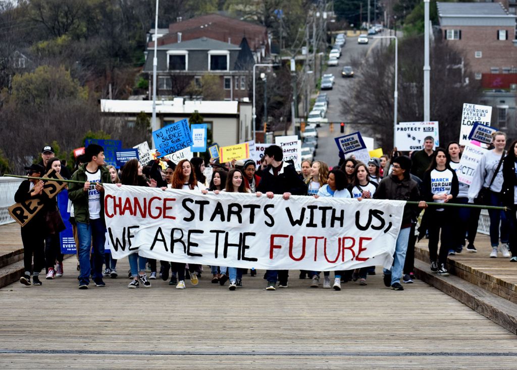 Students carry banner saying that “Change starts with us we are the future” on Saturday