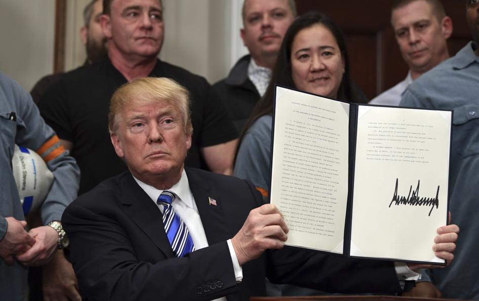 President Donald Trump holds up a proclamation on aluminum during an event in the Roosevelt Room of the White House in Washington Thursday