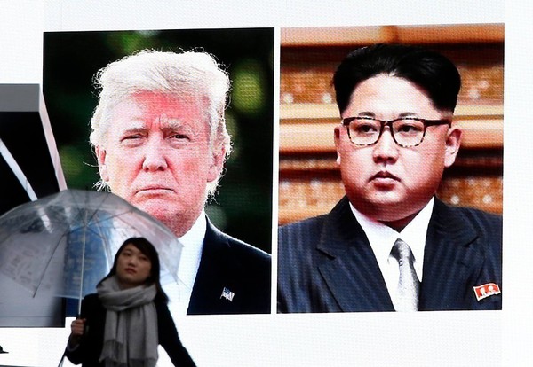 A woman walks by a huge screen showing U.S. President Donald Trump left and North Korea's leader Kim Jong Un in Tokyo Friday