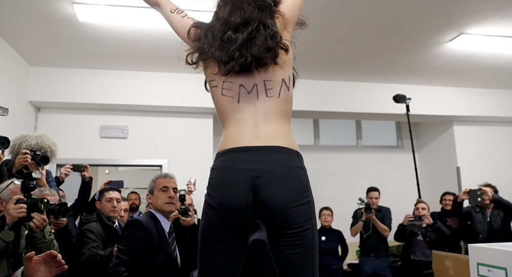 A topless Femen activist protests at a polling station where Italian former premier and leader of Forza Italia party Silvio Berlusconi was about to vote in Milan Italy Sunday