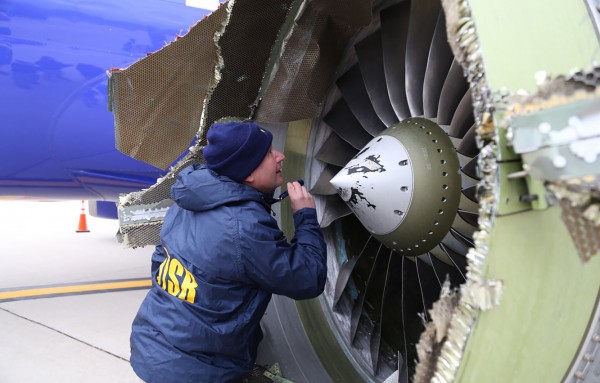 An NTSB investigator on scene examining damage to the engine of the Southwest Airlines plane