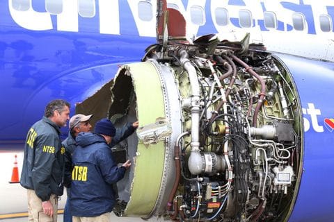 National Transportation Safety Board investigators examine damage to the engine of the Southwest plane