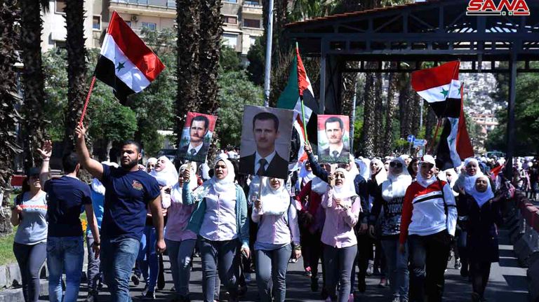 Syrian protesters hold their national flags and portraits