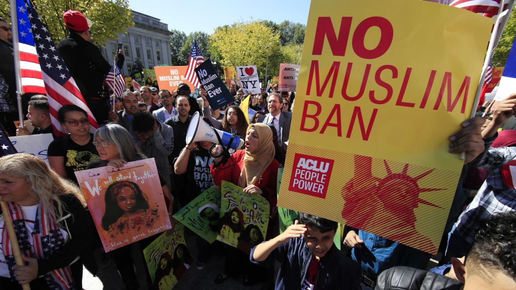 Demonstrators at a rally in Washington D.C. protest the Trump administration's proposed travel ban which goes before the Supreme Court Wednesday