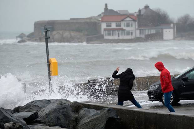 Walkers brave the massive waves yesterday at Sandycove Co Dublin