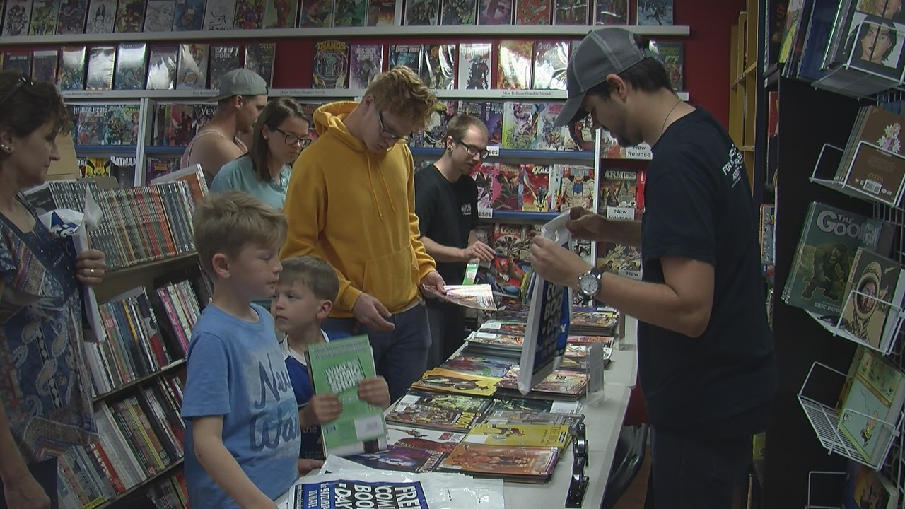 A Fanboy Comics employee gives away comics to a child for Free Comic Book Day