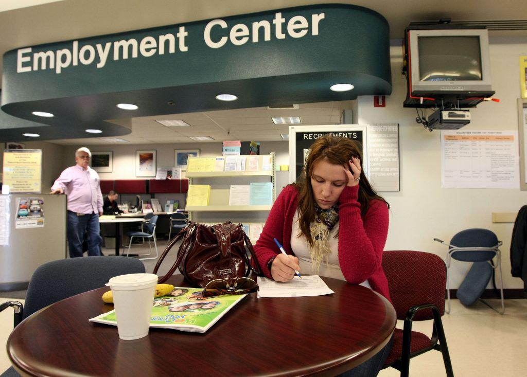 A woman fills out paperwork at an employment center in this file