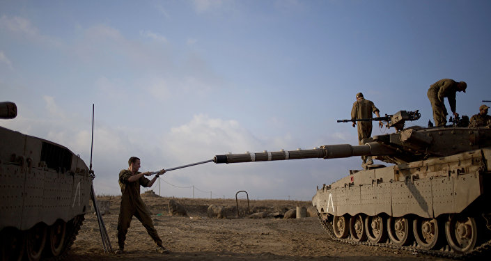 Israeli soldier work on a tank placed near the border with Syria on the Golan Heights