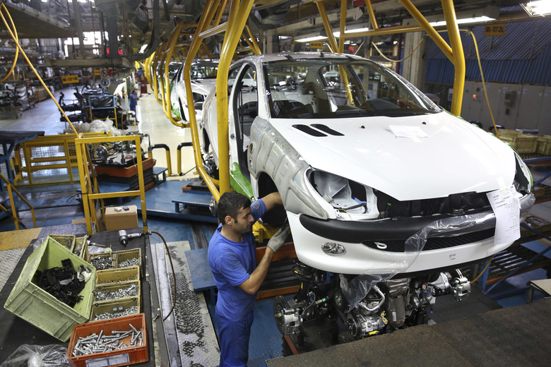 Iranian worker assembles a Peugeot 206 at the state-run Iran Khodro automobile manufacturing plant near Tehran Iran. From brand-new airplanes to oilfields billions of dollars of deals stand on the line for