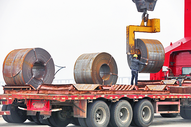 A worker positions a roll of steel plate at a dockyard in Qidong in eastern China’s Jiangsu province. – AP