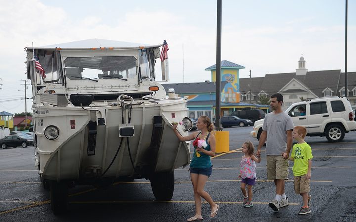 A family of mourners stop to place a flower on a World War II DUKW boat used by Ride The Ducks tours