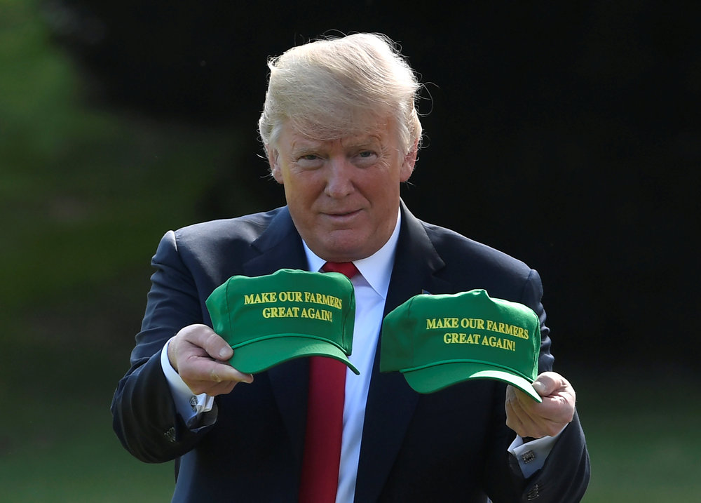 President Donald Trump holds up caps with 'Make Our Farmers Great Again!&#039 as he departs the White House Washington for a day trip to Evansville Indiana