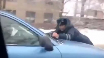 Taxi driver driving his car along with the police officer on his bonnet