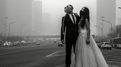 Newly wedded couple posed before camera wearing a GAS MASK