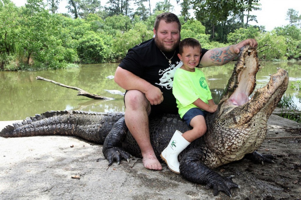 Father is teaching his young son to control the alligator in attempt of continuing their family tradition