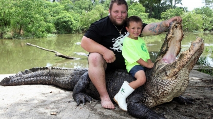 Father is teaching his young son to control the alligator in attempt of continuing their family tradition