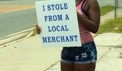 Thief was ordered to stand outside the store from where she stolen goods with a sign board admitting her crime