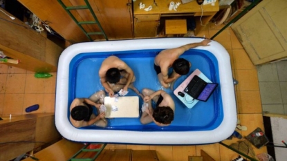 Four Chinese students sets up an inflatable pool inside their room