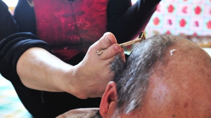 Disabled woman shaves her husband’s head using her feet