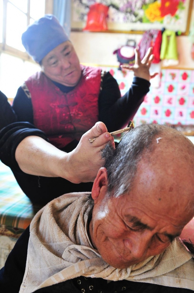 Disabled woman shaves her husband’s head using her feet