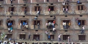 People climbs fifth floor from window to pass note to student sitting inside classroom