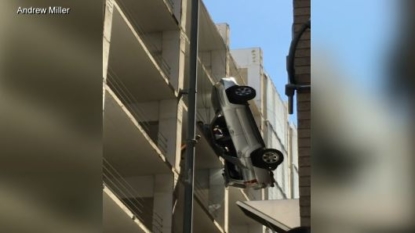 Auto hanging by wheel nine stories over Austin street