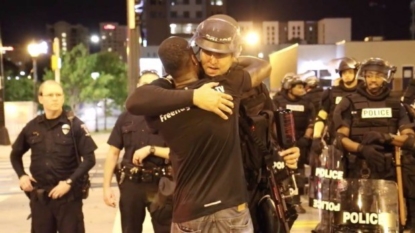 Man gives police in riot gear hugs